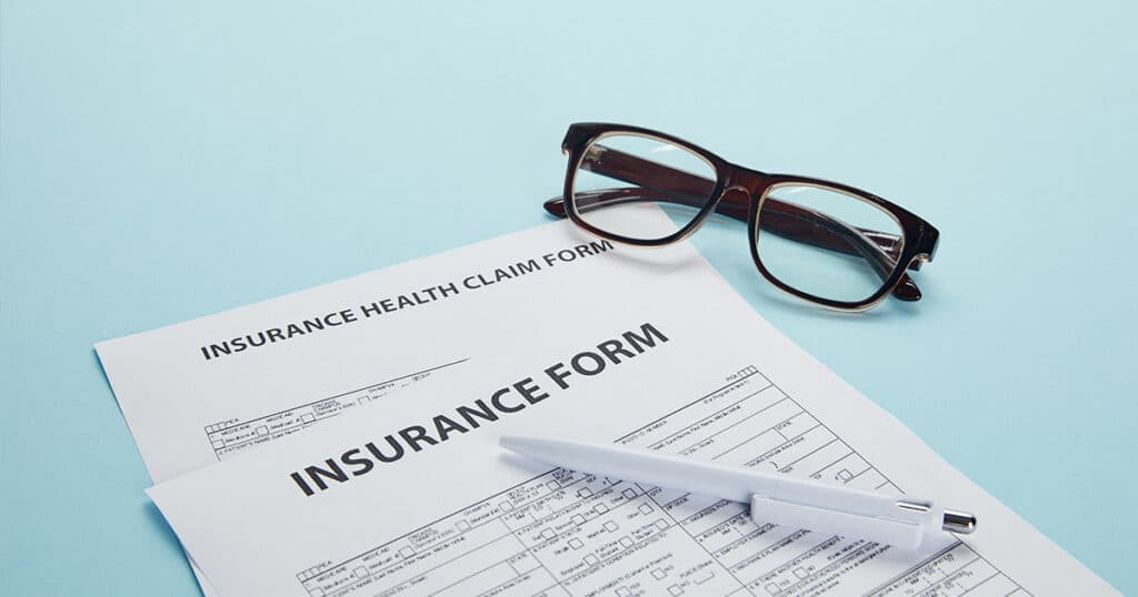 close-up view of insurance form, insurance health claim form, eyeglasses and pen on blue